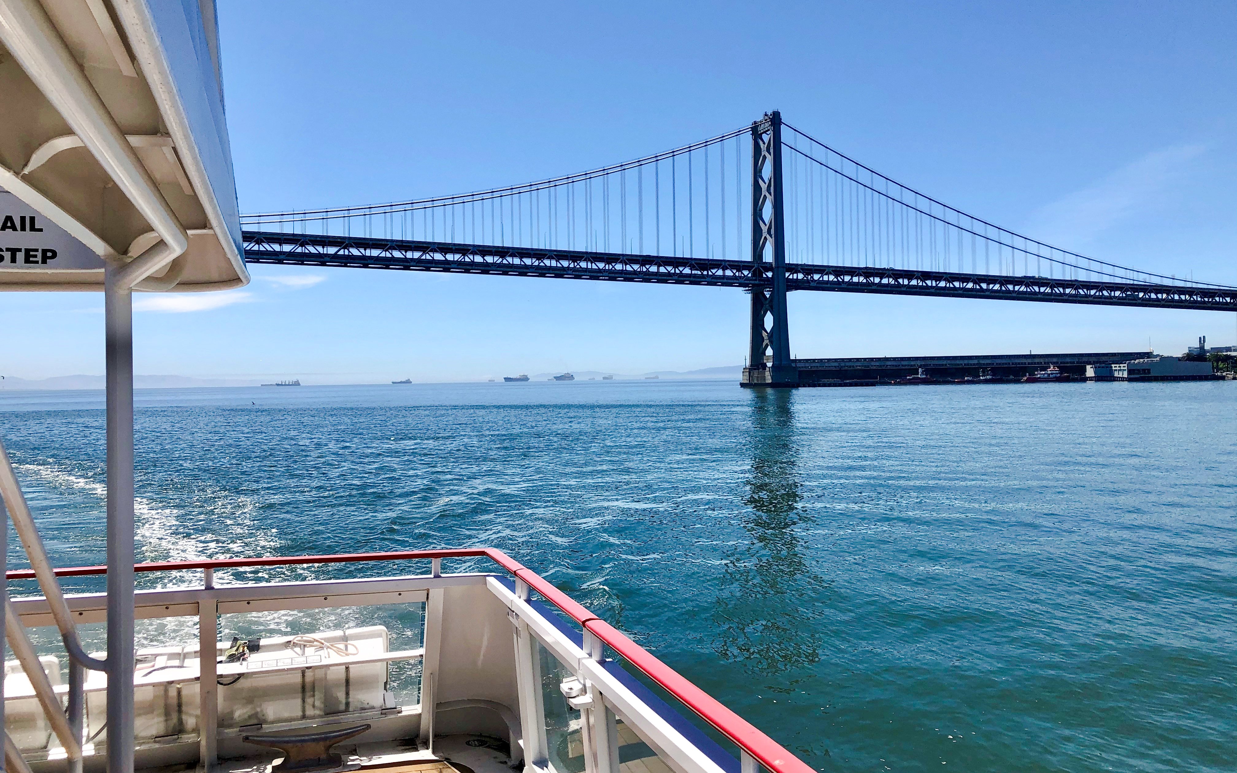 Cruise boat approaching San Francisco Bay Bridge on a sunny day.