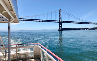 Cruise boat approaching San Francisco Bay Bridge on a sunny day.