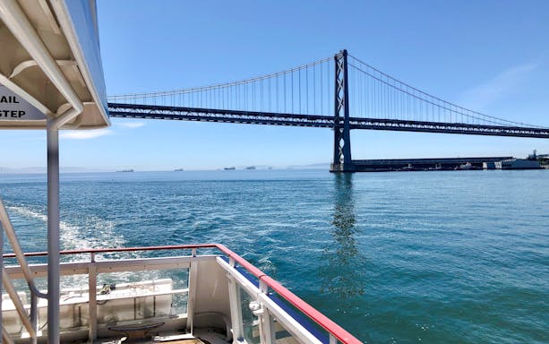 Cruise boat approaching San Francisco Bay Bridge on a sunny day.