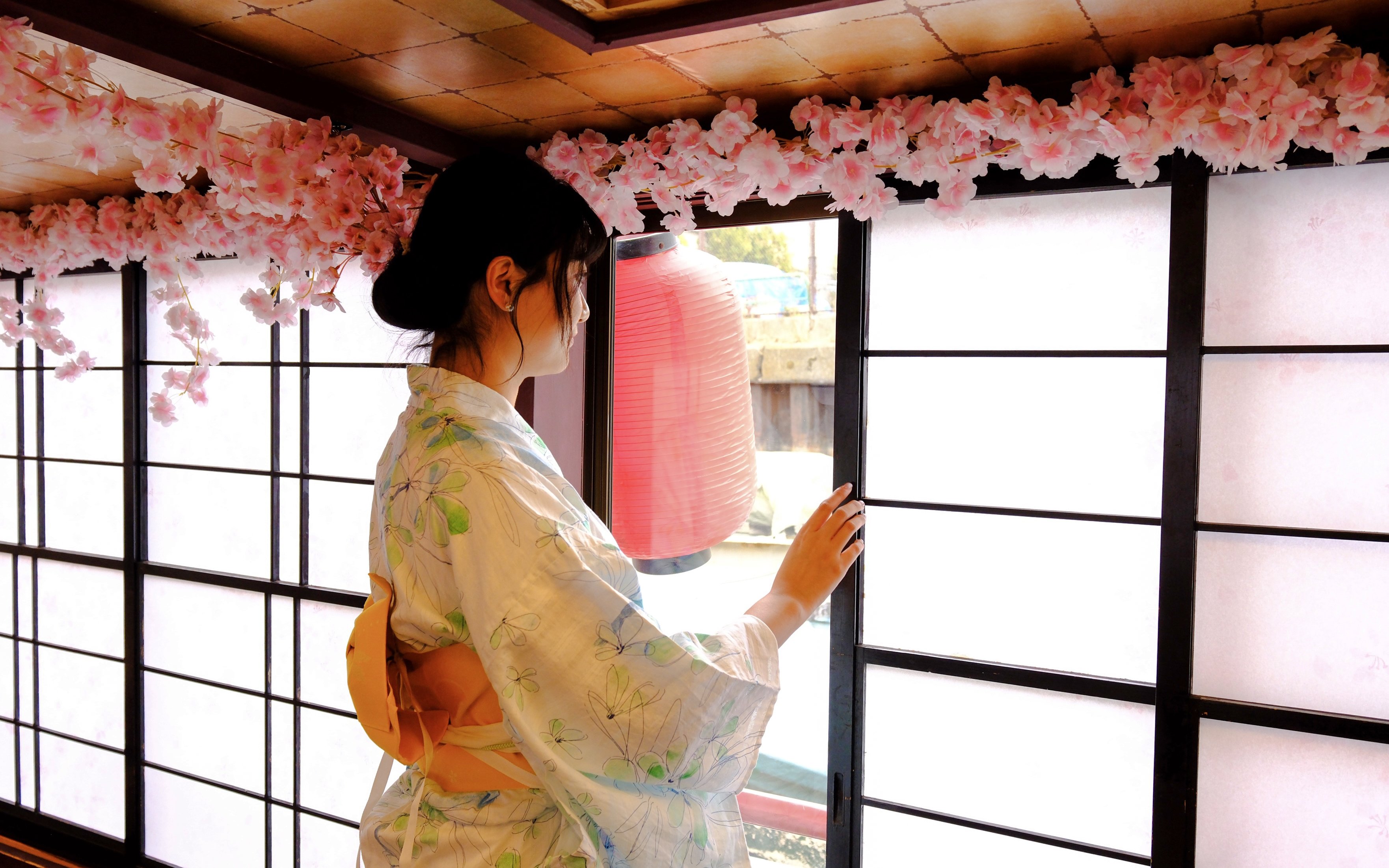 Woman in kimono at Tokyo tea ceremony with cherry blossoms and lantern.