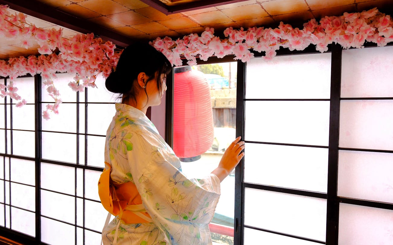 Woman in kimono at Tokyo tea ceremony with cherry blossoms and lantern.