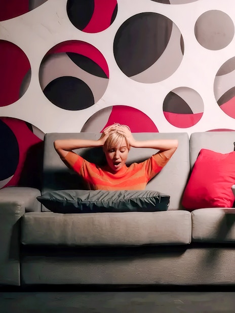 Person sitting on a sofa in the Paradox Sofa room at Paradox Museum Paris with a geometric wall design.