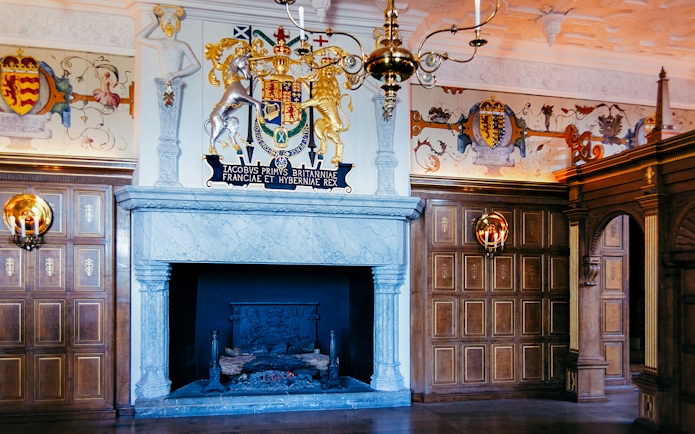 Edinburgh Castle interior with ornate fireplace and royal coat of arms.