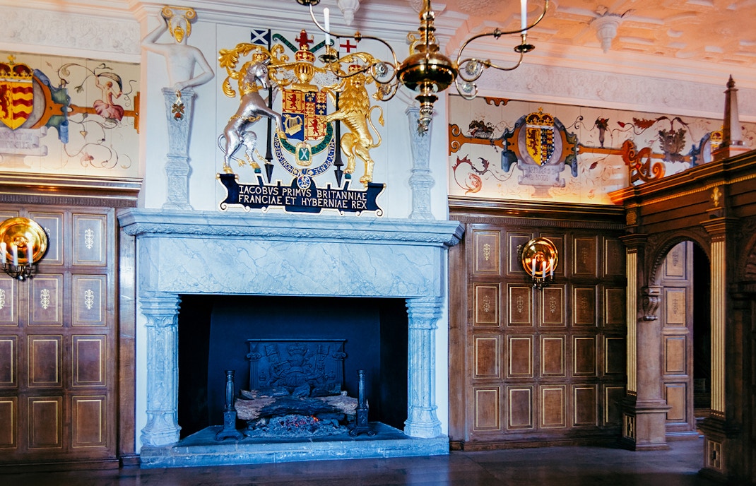 Edinburgh Castle interior with ornate fireplace and royal coat of arms.