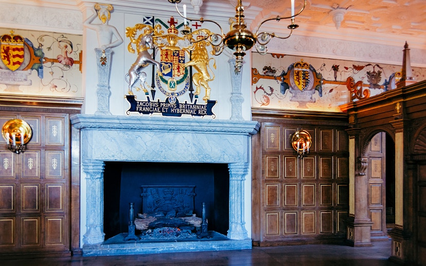 Edinburgh Castle interior with ornate fireplace and royal coat of arms.