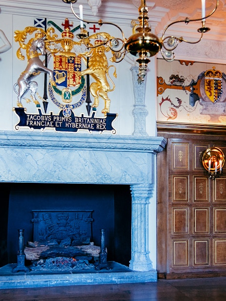 Edinburgh Castle interior with ornate fireplace and royal coat of arms.