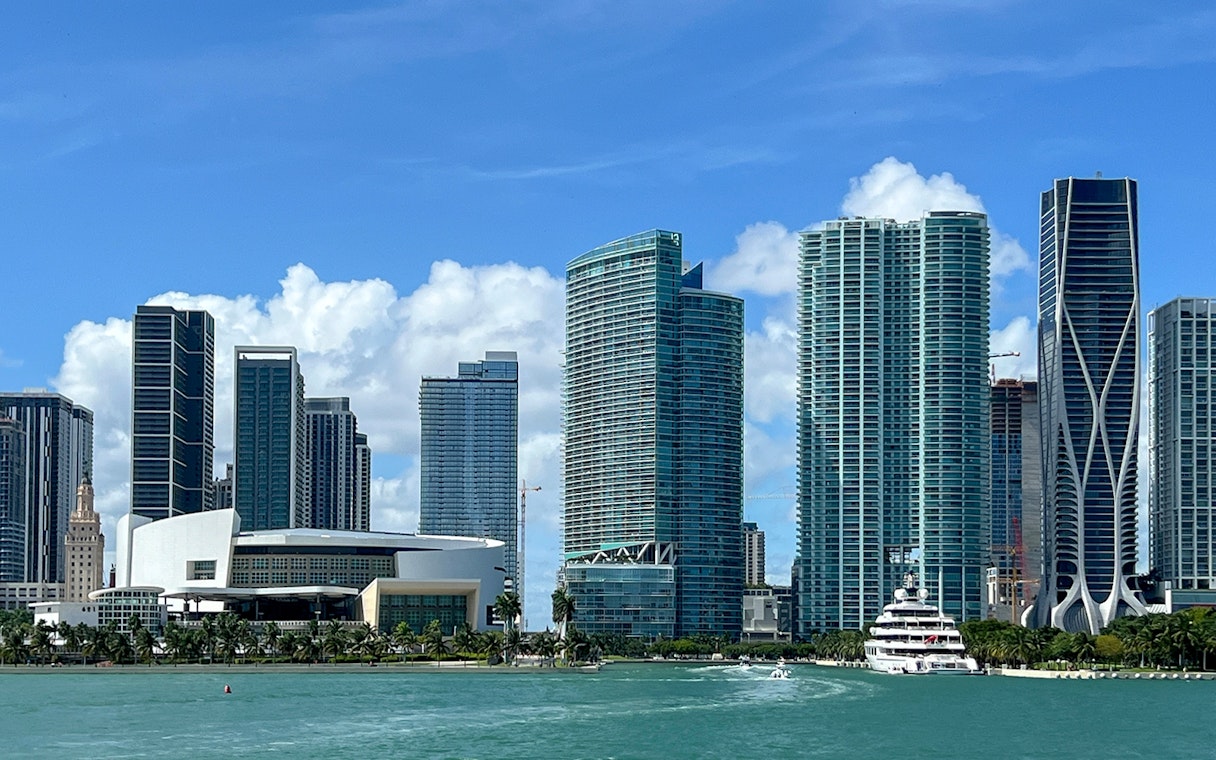 Miami skyline with luxury yacht cruising past high-rise buildings.