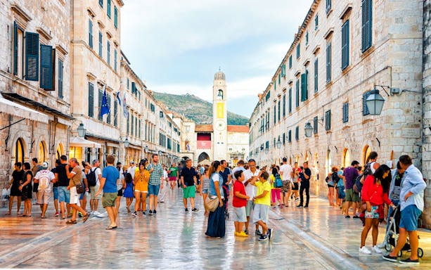 Guests walking through Dubrovnik's main market street with historic buildings.