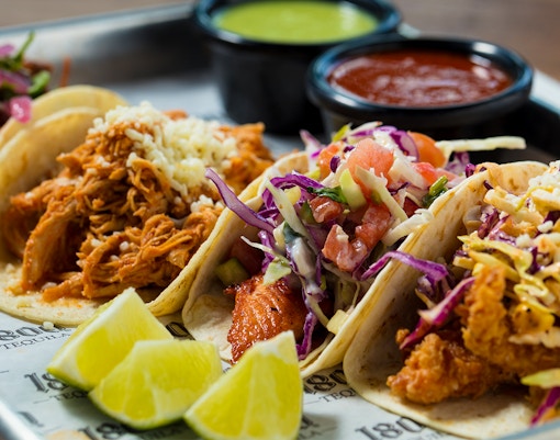Handmade tacos with fresh ingredients displayed on a wooden board in Mexico City.