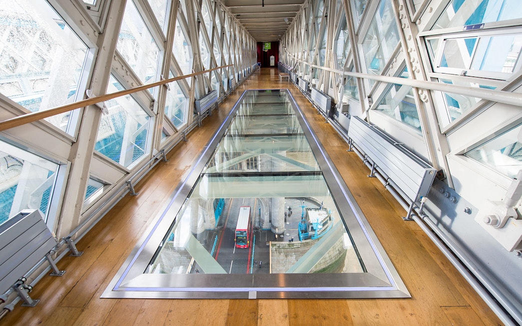 Glass walkway inside Tower Bridge with view of London bus below.