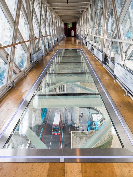 Glass walkway inside Tower Bridge with view of London bus below.