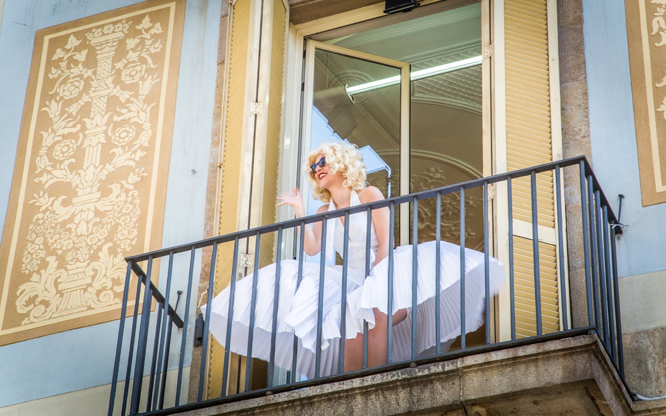 Person in white dress on balcony at Erotic Museum Barcelona.