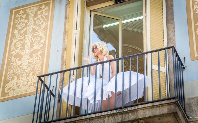 Person in white dress on balcony at Erotic Museum Barcelona.