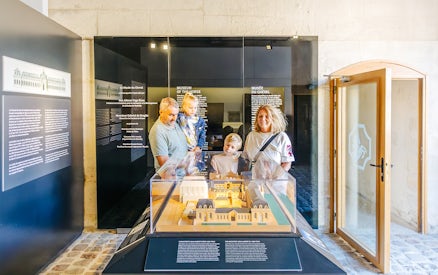 Family viewing a model exhibit at the Chateau of Chantilly museum.