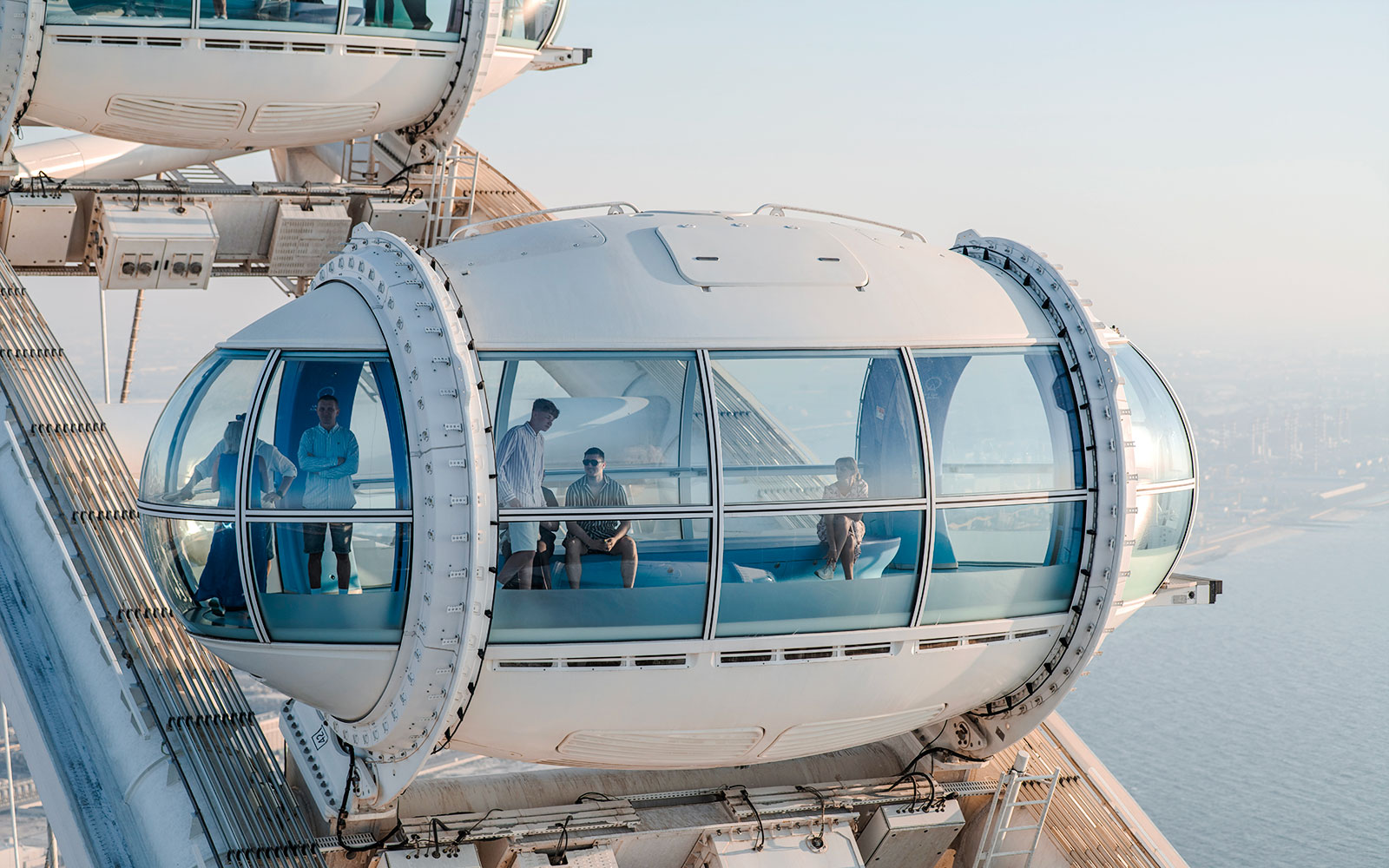 Ain Dubai observation pod with people enjoying views of the city and sea.