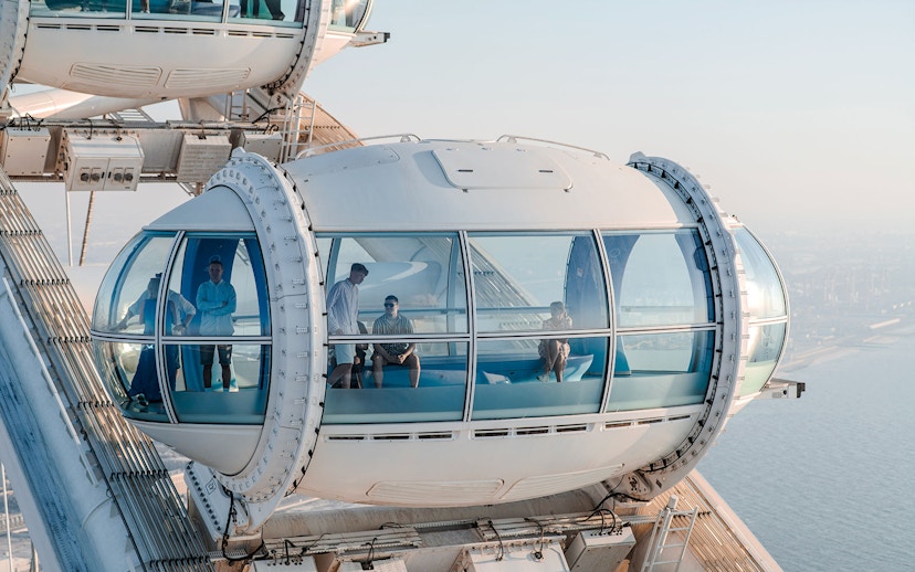 Ain Dubai observation pod with people enjoying views of the city and sea.