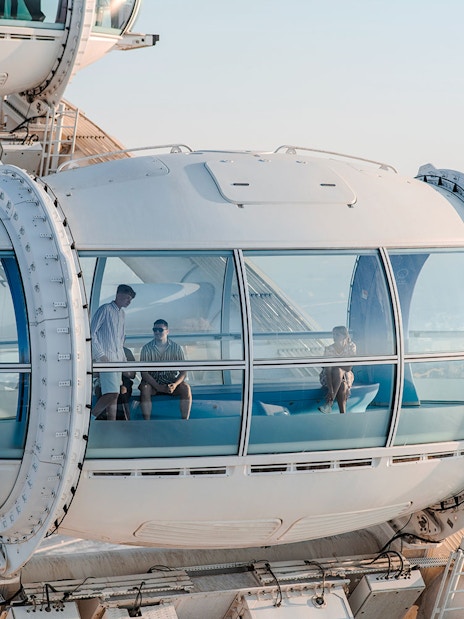 Ain Dubai observation pod with people enjoying views of the city and sea.