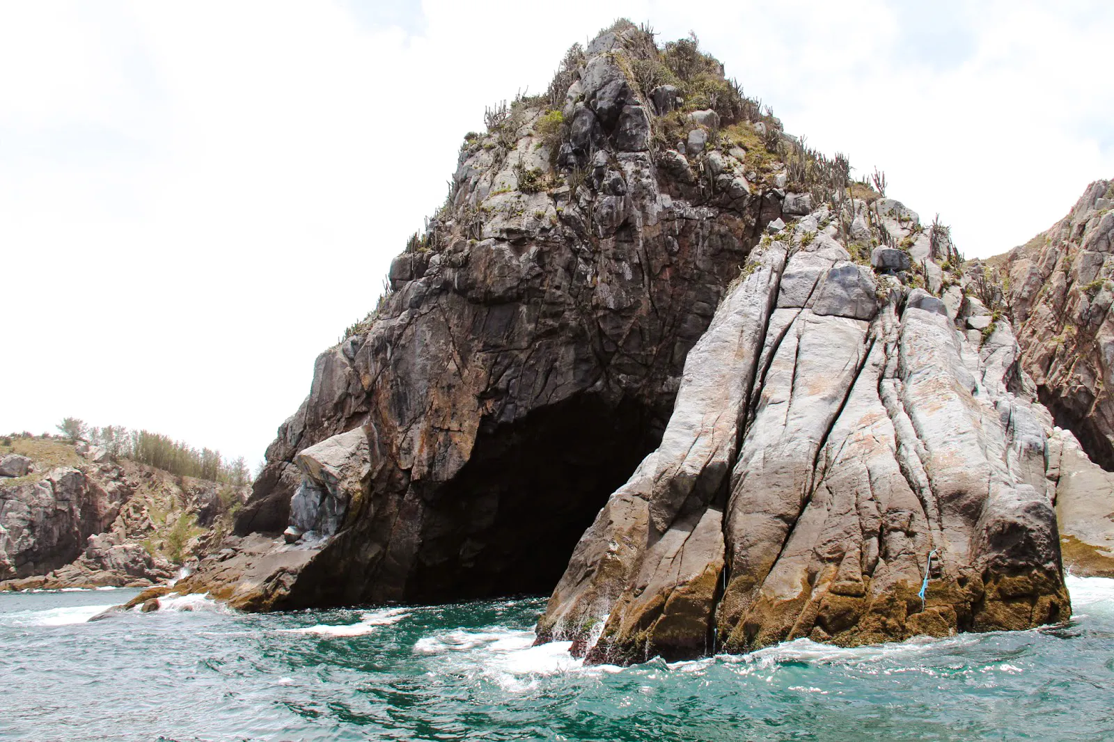Rocky coastal cliffs at Arraial do Cabo, Brazil, with turquoise ocean waves.