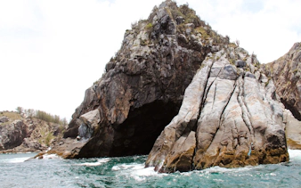 Rocky coastal cliffs at Arraial do Cabo, Brazil, with turquoise ocean waves.