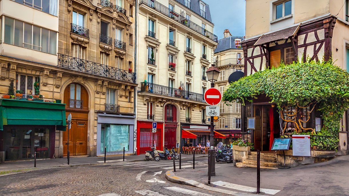 Montmartre street shops with colorful storefronts and pedestrians in Paris, France.