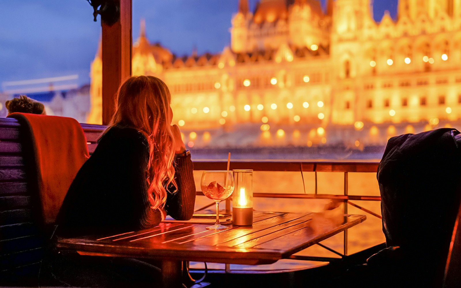 Guests enjoying drinks on a Budapest Danube River nighttime sightseeing cruise.