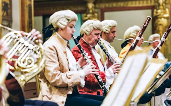 Musicians in period costumes performing at a Mozart orchestra concert.
