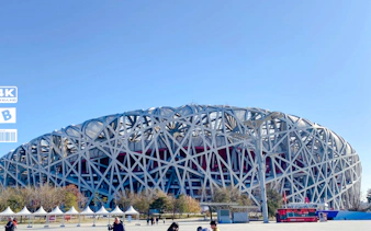 Beijing National Stadium, known as the Bird's Nest, under a clear blue sky.