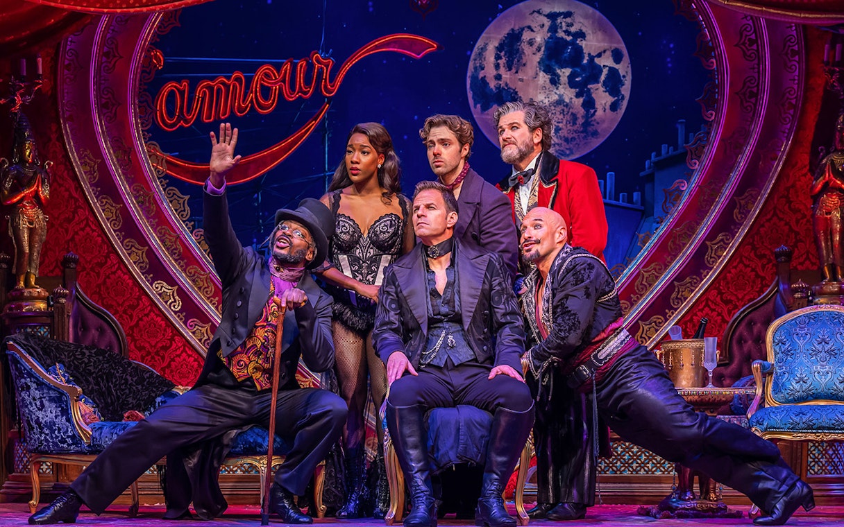 Cast of Moulin Rouge! The Musical on stage with vibrant set design.