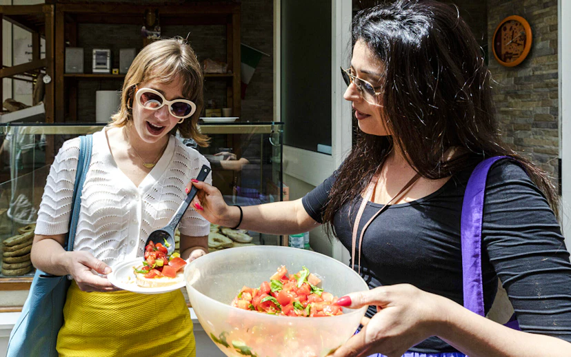 Two women enjoying tomato salad during Food & Market Tour.