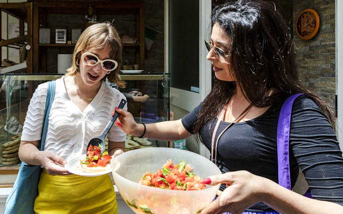 Two women enjoying tomato salad during Food & Market Tour.