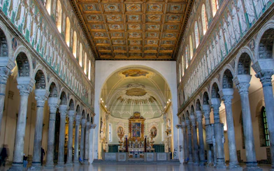 Interior of Basilica di Sant'Apollinare Nuovo in Ravenna, showcasing detailed mosaics and columns.