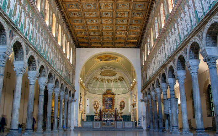 Interior of Basilica di Sant'Apollinare Nuovo in Ravenna, showcasing detailed mosaics and columns.