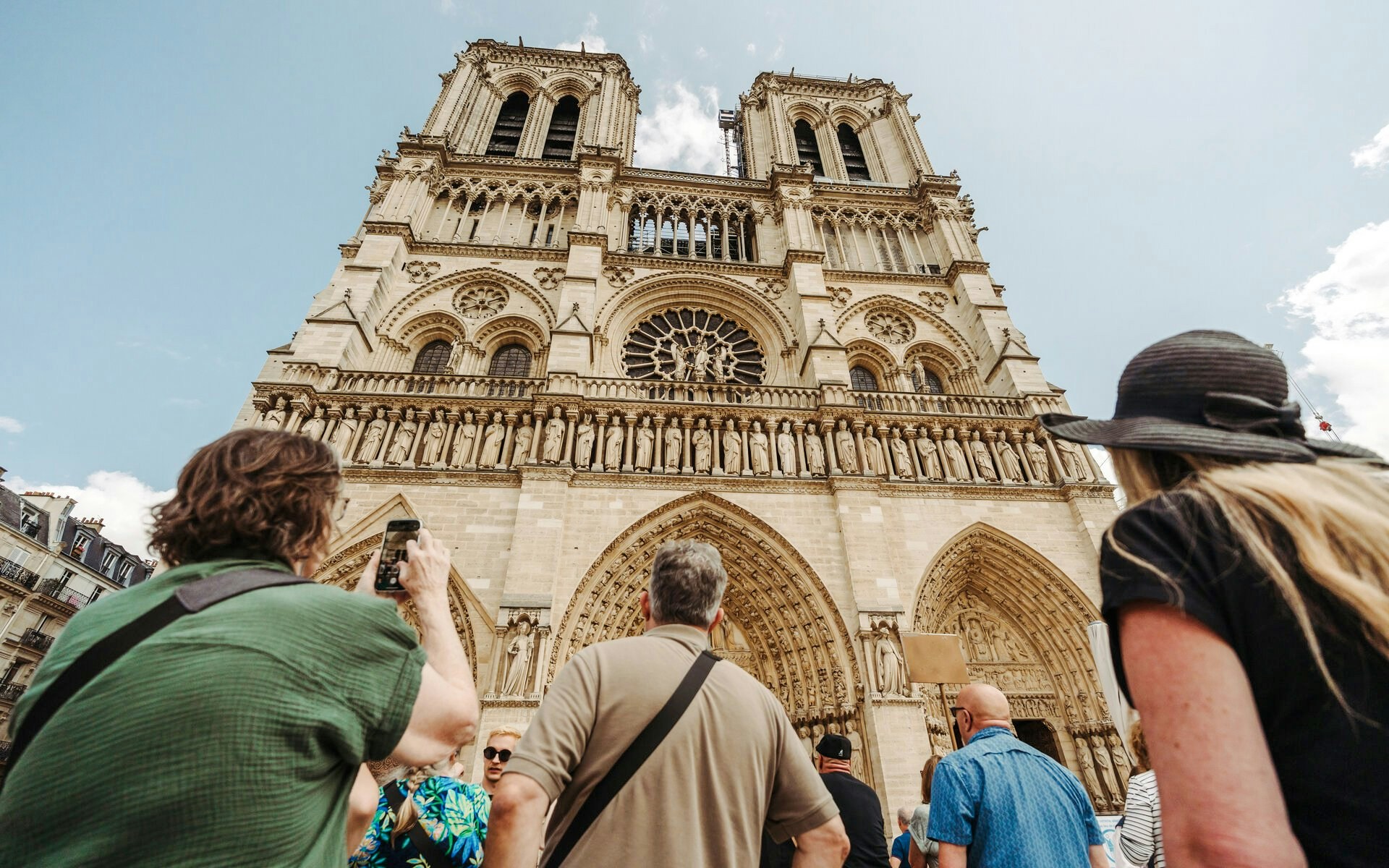 Tourists viewing Notre Dame Cathedral facade in Paris, France.