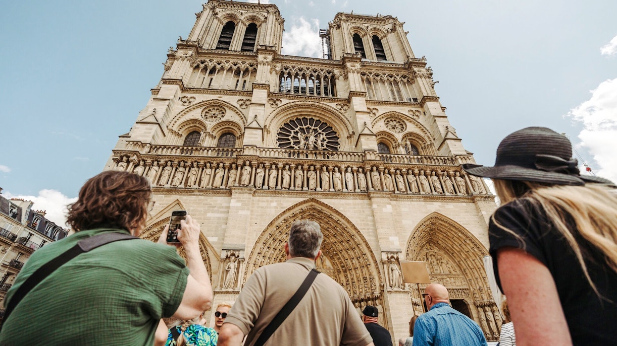Tourists viewing Notre Dame Cathedral facade in Paris, France.