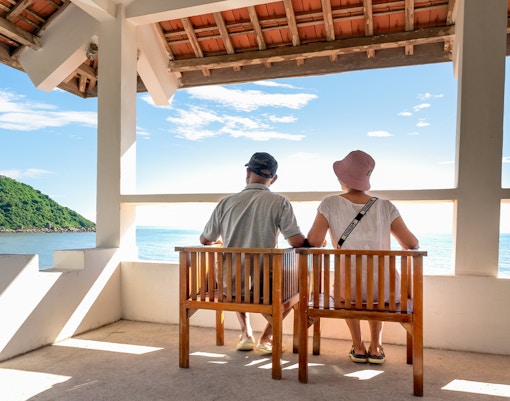 Couple sitting on a bench overlooking the sea at Six Senses Ninh Van Bay, Vietnam.