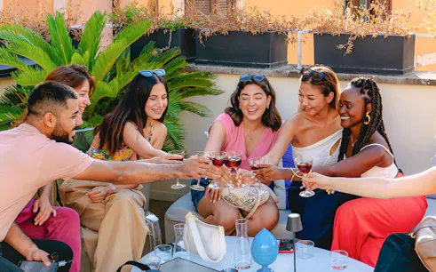 Friends toasting with drinks on a rooftop in Rome.
