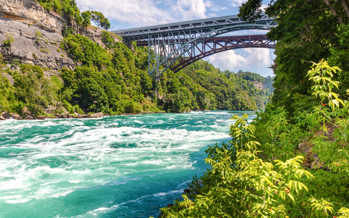 Rapids in the Niagara River near the whirlpool with a bridge in the background.