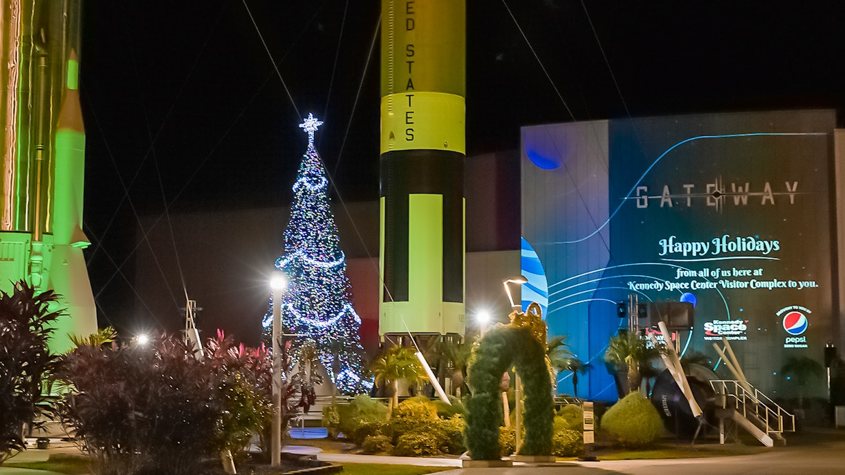 Kennedy Space Center with Christmas decorations, featuring a festive rocket display.