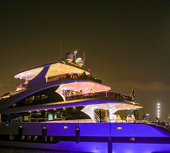 Luxury yacht illuminated at night on a city cruise.