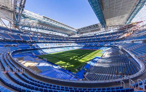 Santiago Bernabéu Stadium interior with empty seats and green field in Madrid, Spain.