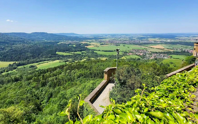 View from Hohenzollern Castle overlooking lush green landscape and distant hills, Germany.
