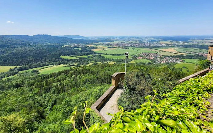 View from Hohenzollern Castle overlooking lush green landscape and distant hills, Germany.
