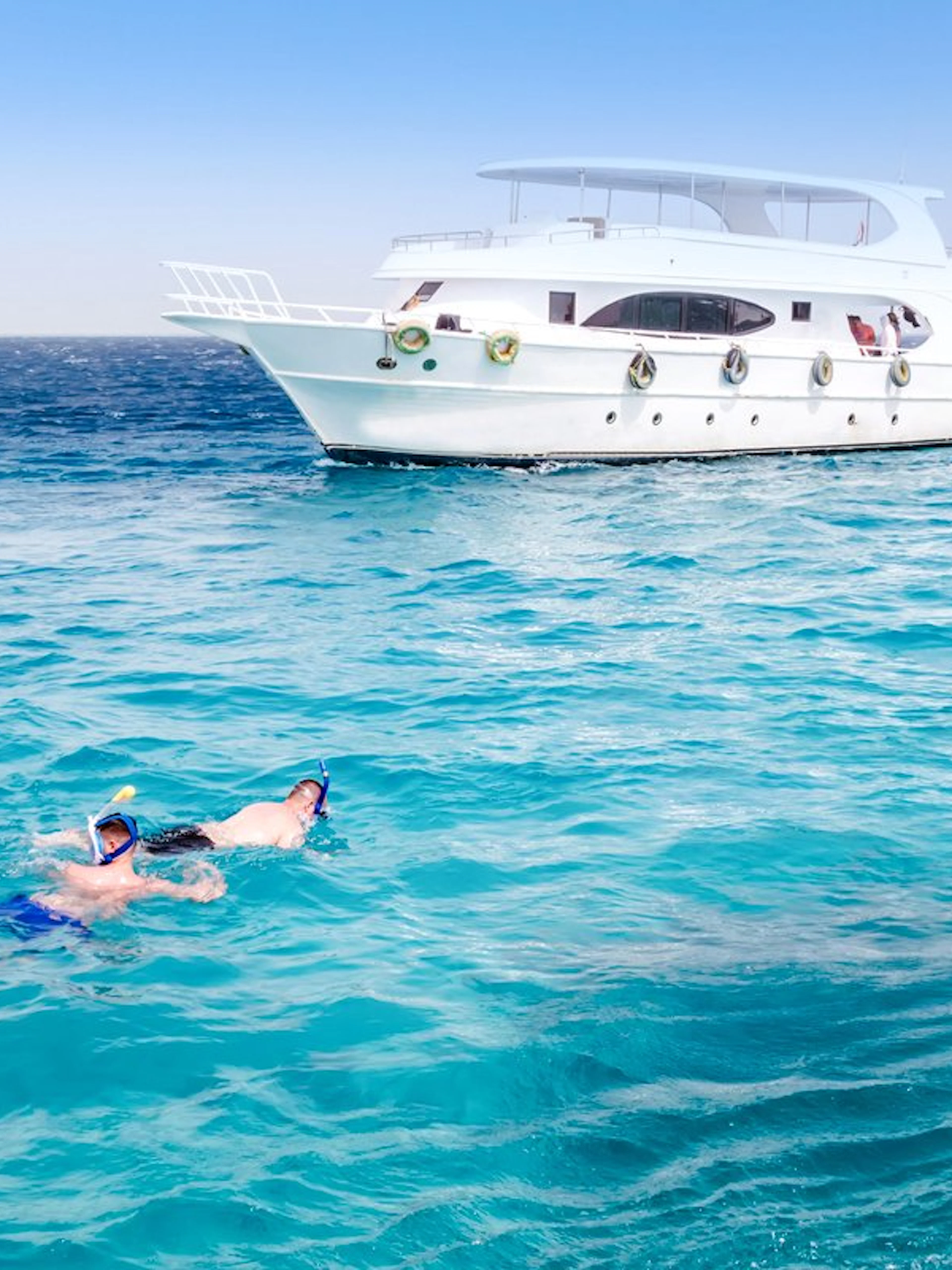 Friends snorkelling in the Red Sea near a boat during Dolphin Watching Tour, Hurghada.