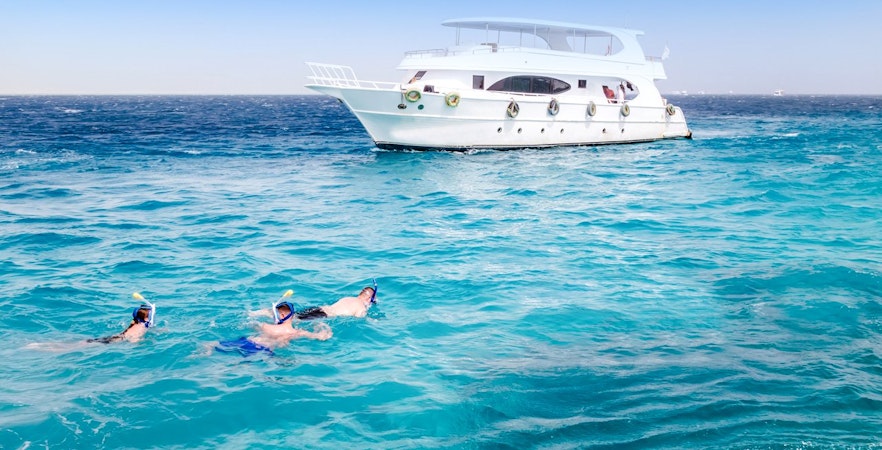 Friends snorkelling in the Red Sea near a boat during Dolphin Watching Tour, Hurghada.
