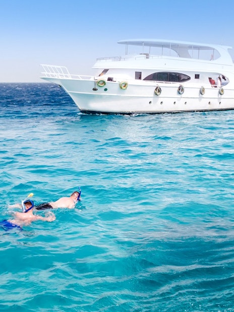Friends snorkelling in the Red Sea near a boat during Dolphin Watching Tour, Hurghada.