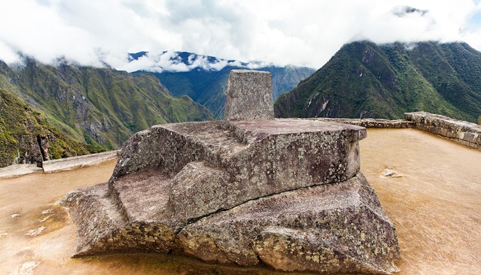 Intihuatana stone at Machu Picchu with Andes mountains in the background, Peru.