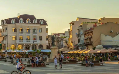 Constanța Old Town square with people and historic buildings at sunset.