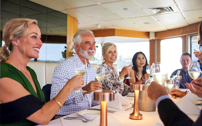 Group dining on a Sydney Harbour cruise with wine and scenic views.