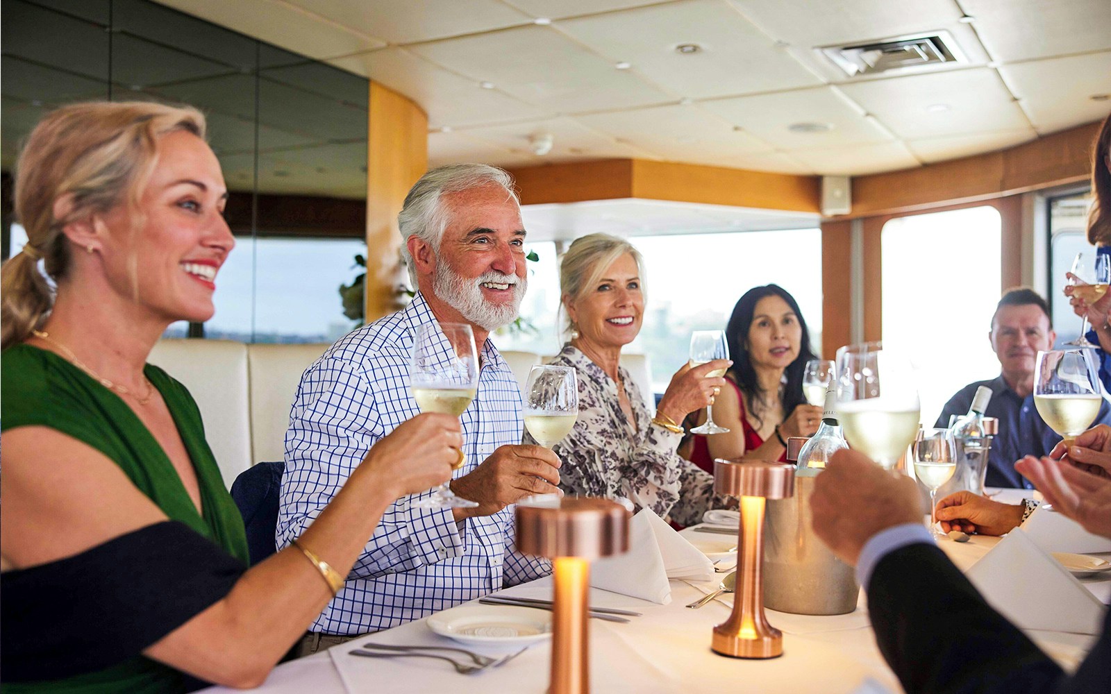 Group dining on Sydney Harbour cruise with city skyline in background.