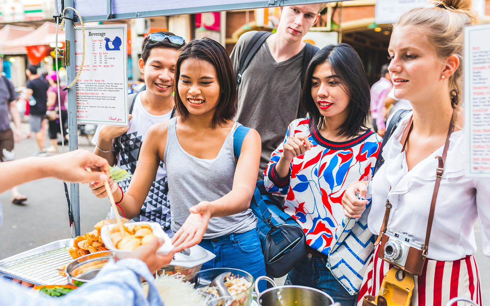 Tourists exploring Khao San Road, Bangkok, enjoying vibrant street food stalls.